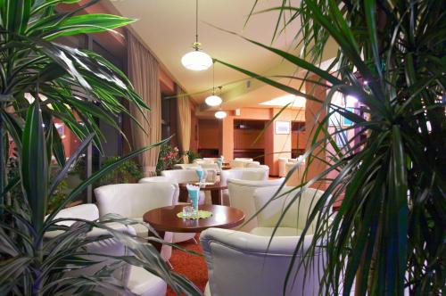 a restaurant with white chairs and tables and plants at Geovita Dąbki in Dąbki