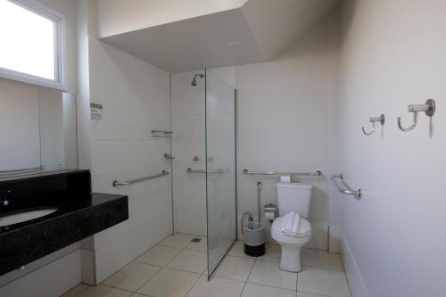 a bathroom with a toilet and a glass shower at Hotel Gralha Azul in Presidente Prudente