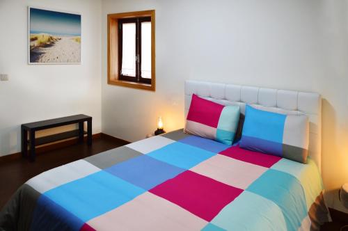 una camera da letto con un grande letto con cuscini colorati di Casa São Pedro a Caminha