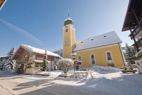 a yellow church with a clock tower in the snow at Haus Veronika - Appartements by Miha in Westendorf