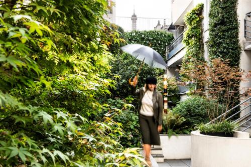 
a woman walking down a street holding an umbrella at Jardins Eiffel in Paris

