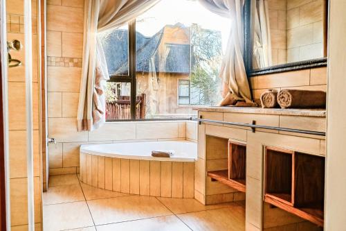 eine Badewanne in einem Raum mit Fenster in der Unterkunft Zebula 8 Bedroom Lodge – IV1 in Mabula