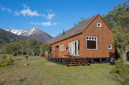 a wooden house in a field with mountains in the background at Casa Cerro Castillo in Villa Cerro Castillo