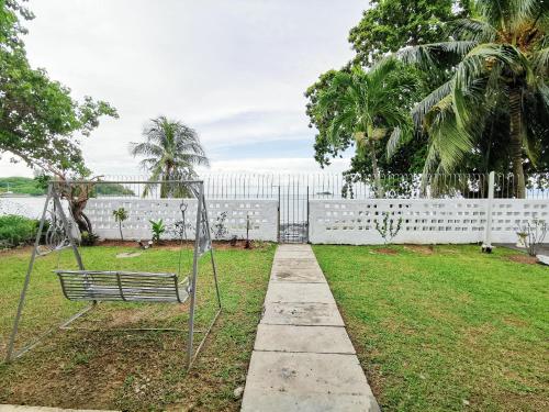 a park with a bench and a white fence at Little Heaven by Sky Hive, A Beach Front Bungalow in Tanjung Bungah