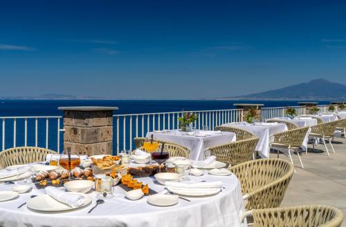 a table with white plates and food on a balcony at Hotel Lorelei Londres in Sorrento