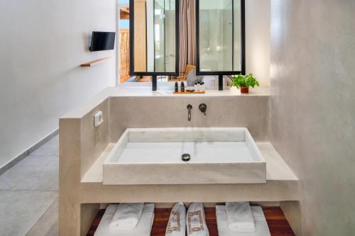 a bathroom with a large bath tub with a window at Callia Retreat Suites - Adults Only in Fira