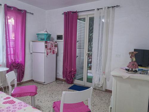 アルカモ・マリーナにあるCasaulente Mareのピンクのカーテンと白い冷蔵庫付きのキッチンが備わります。