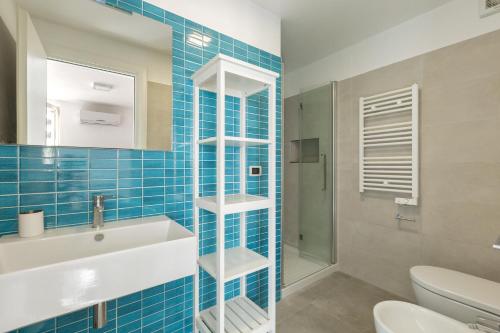 a blue tiled bathroom with a sink and a toilet at Villa Diamante by BarbarHouse in Maruggio