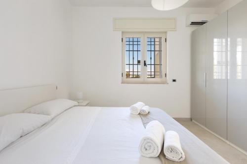 a white bedroom with two white towels on a bed at Villa Diamante by BarbarHouse in Maruggio