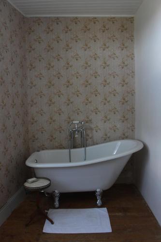 uma banheira branca na casa de banho com papel de parede em Grange Bleuet em Aubeterre-sur-Dronne