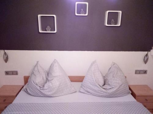 a bed with white pillows and pictures on the wall at Landhaus Tirol in Presseggersee