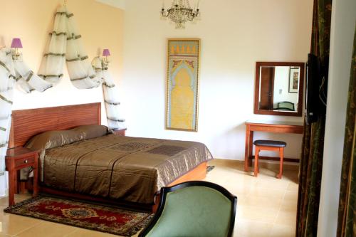 1 dormitorio con cama, espejo y silla en Riad Dar Achaach, en Tetuán