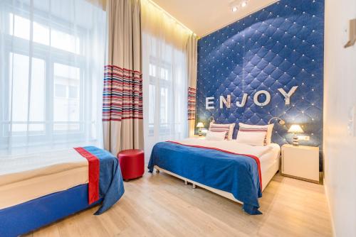 a hotel room with two beds and a wall with the word enjoy at Estilo Fashion Hotel Budapest in Budapest