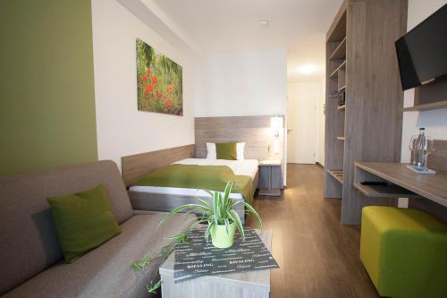 a hotel room with a bed and a couch at Wein & Bett Weihbrecht in Bretzfeld