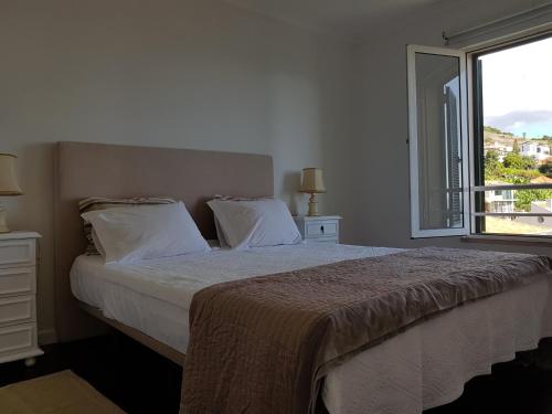 een slaapkamer met een groot bed en een raam bij The Sunrise of your Dreams with Total Ocean View in Funchal