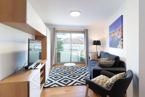 a living room with a couch and a tv at Deluxe Modern Flat with Balcony by Host Wise in Porto
