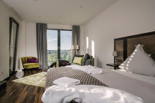 KörperichにあるBoutiquehotel Genusswerk Eifelのベッドと大きな窓が備わるホテルルームです。