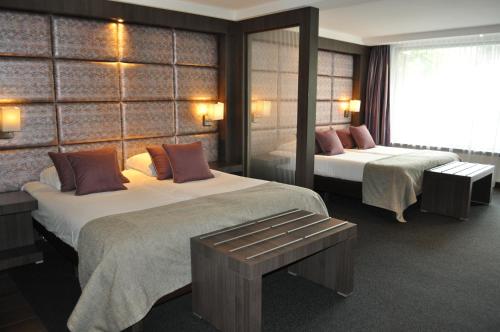 a hotel room with two beds and a mirror at Van der Valk Hotel Nuland - 's-Hertogenbosch in Nuland