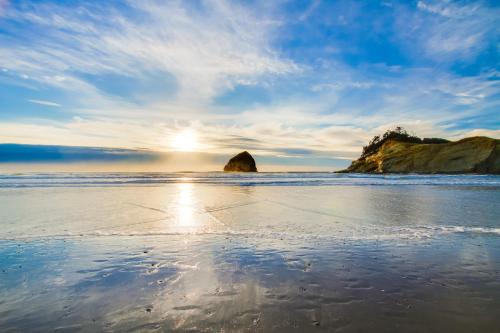 a beach with the sun shining on the water at Beachcomber's Paradise in Pacific City