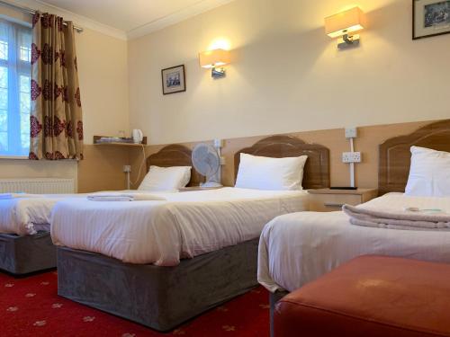 a hotel room with two beds and a window at Twickenham Guest House in Twickenham