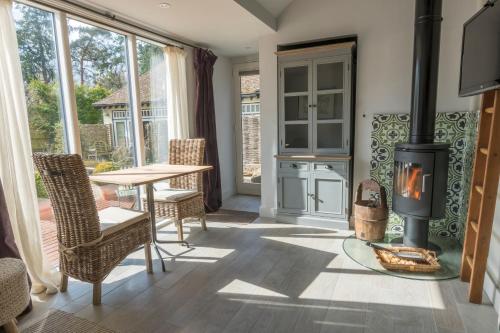 a living room with a fireplace and a table and chairs at Daisybank Cottage Boutique Bed and Breakfast in Brockenhurst