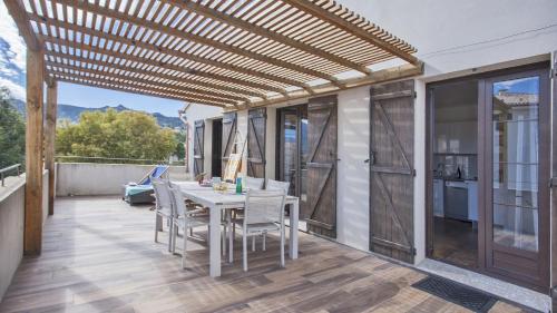 eine Pergola auf einer Terrasse mit einem Tisch und Stühlen in der Unterkunft Laniella location in Calvi