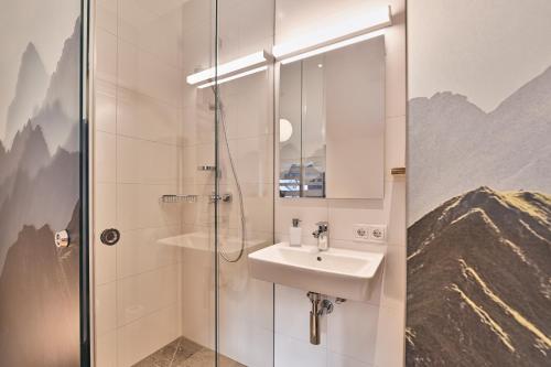 La salle de bains est pourvue d'un lavabo et d'une douche. dans l'établissement Wald 12 Ferienhaus, à Wald am Arlberg