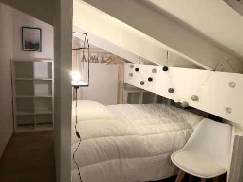 um quarto com uma cama branca e uma cadeira branca em L'Aire des montagnes em Bolquere Pyrenees 2000