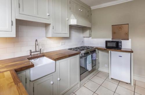 a kitchen with white cabinets and a sink and a stove at Ivory House - Stunning Central Townhouse in Bath
