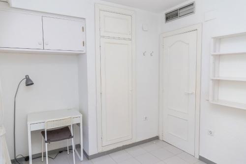 a white kitchen with a desk and a chair at Oasis Club II Triplex Apartment by Rock Rentals in Jávea