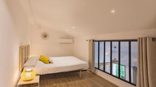 um quarto com uma cama e uma grande janela em Laniella location em Calvi