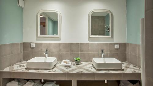 two sinks in a bathroom with two mirrors at Laniella location in Calvi