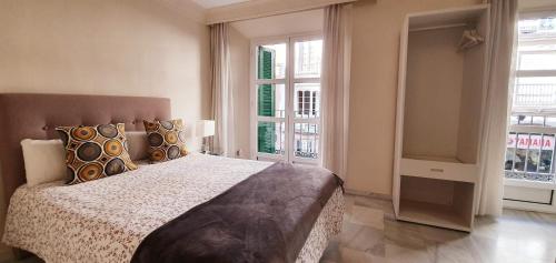 - une chambre avec un grand lit et 2 fenêtres dans l'établissement Fan Flat Carretería, à Malaga