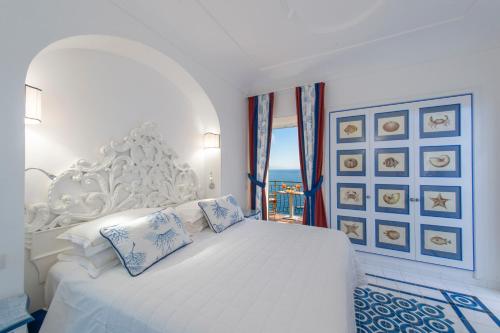 a white bedroom with a white bed and a window at Hotel Onda Verde in Praiano