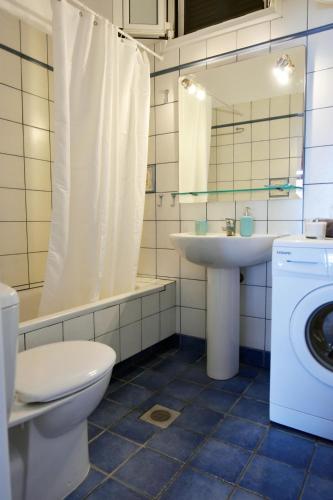 a bathroom with a toilet a sink and a washing machine at The Stone Beach House in the area of Kampi, Koundouros in Ioulis
