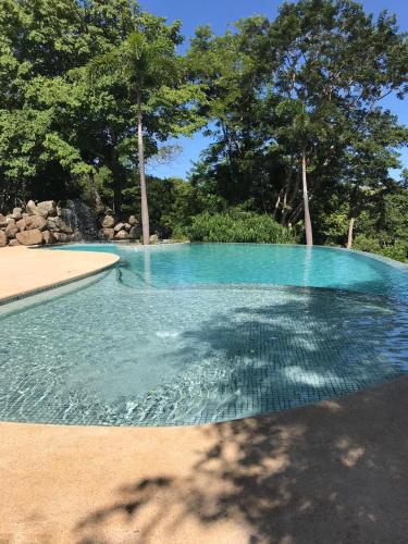 a pool of blue water with trees in the background at Mikado Natural Lodge in Playa Avellana
