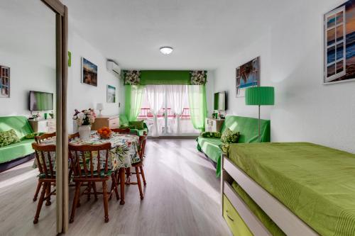 - une chambre avec un lit vert, une table et des chaises dans l'établissement Apartment Studio Playa del Cura, à Torrevieja