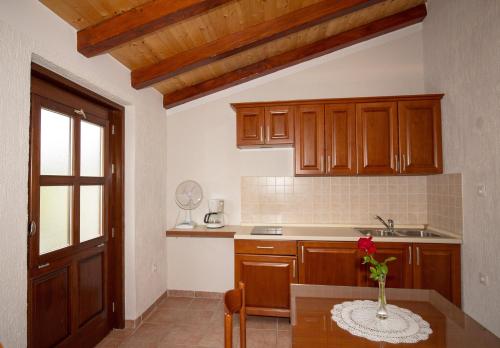 a kitchen with wooden cabinets and a table with a vase on it at Apartment La roza in Funtana