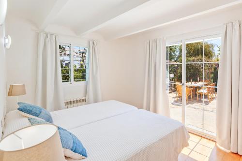 パルマ・デ・マヨルカにあるVilla Bellverの白いベッドルーム(ベッド1台付)、パティオが備わります。
