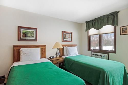 two beds in a room with green sheets at Cleerwood Village #252 in Eagle River