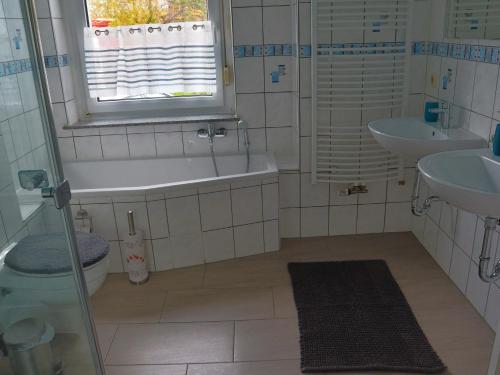 baño con bañera, 2 lavabos y ventana en Ferienwohnung Familie Bulst en Naumburg (Saale)