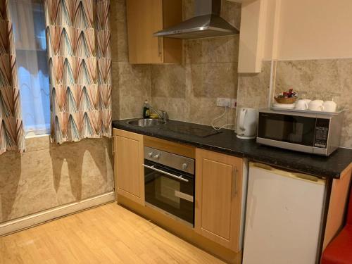 uma cozinha com um micro-ondas e um lavatório em Twickenham Guest House em Twickenham