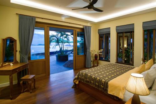 a bedroom with a bed and a desk and windows at Villa Moonstone in Laem Set Beach