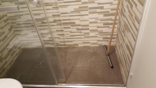 une douche avec une porte vitrée dans une salle de bain dans l'établissement Chez marilyn, à Deauville