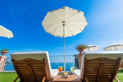 two chairs and a table with an umbrella at Hotel Onda Verde in Praiano