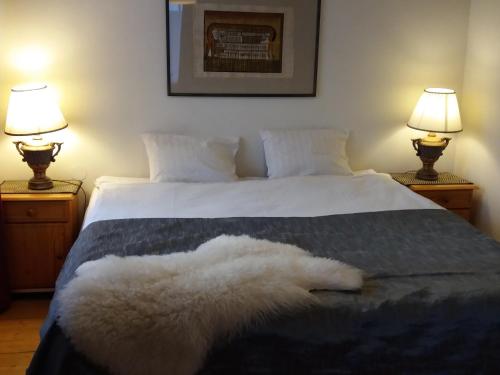 a bedroom with a bed with white sheets and two lamps at White Villa in Tallinn
