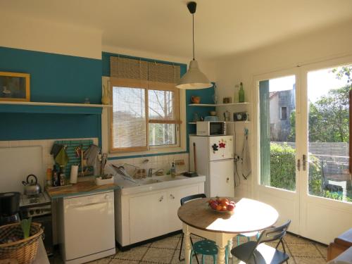 une cuisine avec une table et un réfrigérateur blanc dans l'établissement Maison lumineuse et spacieuse avec jardin arboré, à La Valette-du-Var