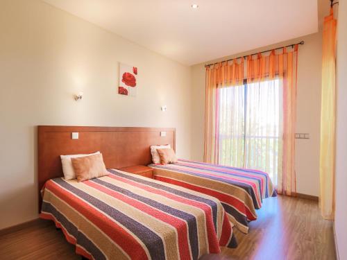 two beds in a room with a window at V4, Villa Jardins Branqueira4 near Beach, Albufeira in Albufeira