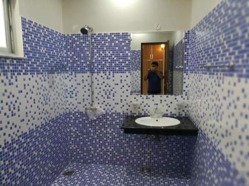 a blue tiled bathroom with a sink and a mirror at royal cottage guest house in Islamabad