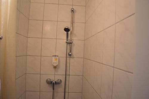 a shower in a bathroom with white tiles at Hotel Mercedes/Centrum in Hamburg